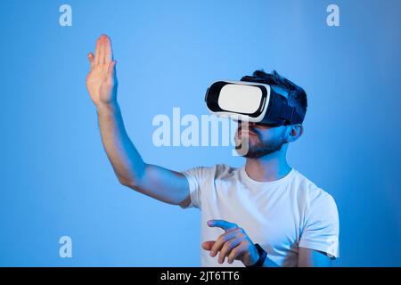 Uomo bearded che indossa occhiali VR e gioca a un videogioco con un amico in metaverse. Tecnologia VR per l'intrattenimento, l'apprendimento e i videogame. Foto Stock