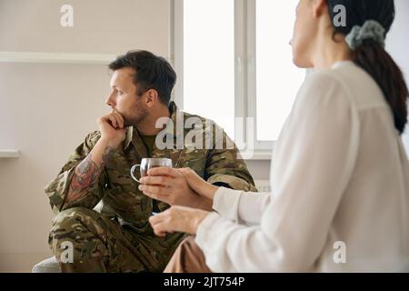 La donna sta confortando un giovane soldato sconvolto Foto Stock