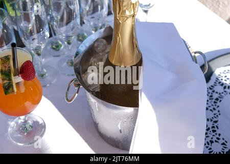 Bottiglia di champagne in secchio di ghiaccio con bicchiere di champagne, cocktail di frutta, pronta per servire, vacanza tropicale. Foto Stock