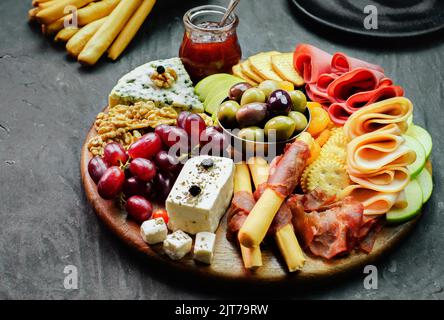 Il piatto di formaggi perfetto con varietà di deliziosi frutti freschi, marmellata, noci, cracker, burro e formaggio liscio e frutta secca. Foto Stock