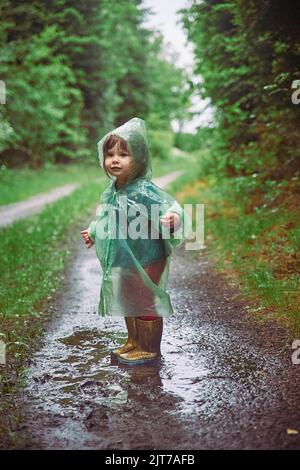 Bambino affascinante in impermeabile nella foresta serale in Danimarca Foto Stock