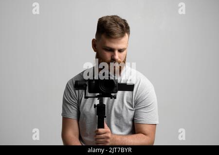 Regista professionale con una fotocamera dslr su stabilizzatore a 3 assi. Concetto di filmmaking, videografia, hobby e creatività. Foto Stock
