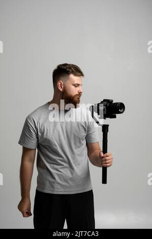 Cineasta professionale con una fotocamera dslr su stabilizzatore a 3 assi. Concetto di filmmaking, videografia, hobby e creatività. Foto Stock