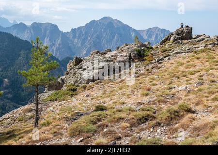 Escursionista fare una pausa sulla GR20 di fronte a un magnifico panorama, Corsica, Francia Foto Stock