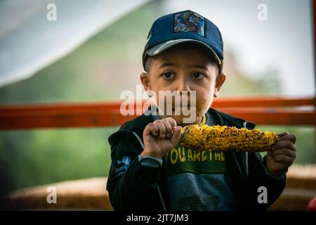 Ragazzo mangiare mais con passione Foto Stock