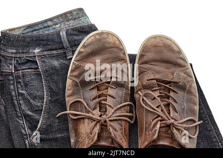 Scarpe in pelle marrone vintage e jeans neri elegantemente stressati isolati su sfondo bianco Foto Stock