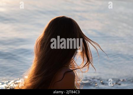 Lungo capello di una donna primo piano si sviluppa nel vento sullo sfondo del mare Foto Stock