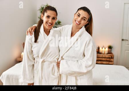 Due donne che indossano un accappatoio che si abbraccia in piedi presso il centro di bellezza Foto Stock