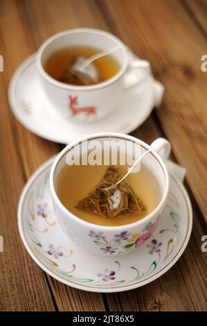 Bustine di tè piramidale prodotte in due tazze jo sfondo in legno verticale Foto Stock