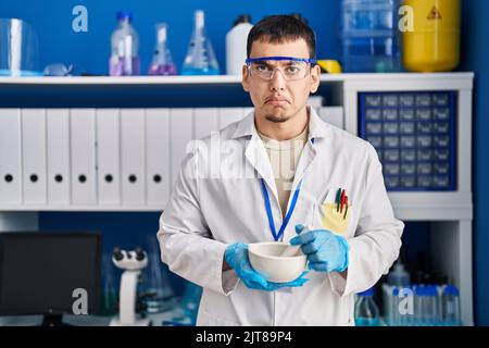 Giovane arabo che lavora al laboratorio scienziato depresso e si preoccupa per il disagio, piangendo arrabbiato e impaurito. Espressione triste. Foto Stock