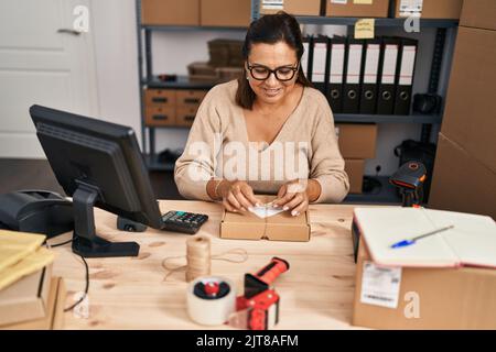 Medio età ispanica donna ecommerce business worker preparare il pacchetto in ufficio Foto Stock