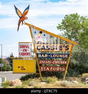 Lo storico moderno cartello al neon di metà secolo sulla strada per Cassie's Bar and Lounge a Cody, Wyoming. Il segno per il club cena offre bistecche, pollo, Foto Stock