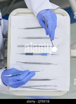 Strumenti essenziali del settore dentale. Ripresa ad angolo elevato di un dentista non riconoscibile che lavora con un vassoio di strumenti chirurgici. Foto Stock