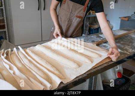 Il processo di fabbricazione di baguette francesi tradizionali in un panificio artigianale. Pane di prova su tessuto. Vista frontale. Foto Stock