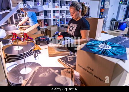 22 agosto 2022, Meclemburgo-Pomerania occidentale, Güstrow: I dipendenti della società discografica 'questione di fatto' controllano e imballano i record appena pressati nelle loro copertine. L'azienda, che attualmente ha cinque dipendenti, produce record per diverse settimane in un'ex sala patata che ha dovuto essere ampiamente convertito per la produzione di dischi. Con una forza di 150 tonnellate, i dischi di lunga durata sono prodotti sulle presse a 200 gradi Celsius da cloruro di polivinile (PVC). Ogni anno devono essere premuti tra 250.000 e 300.000 record. Secondo l'Associazione tedesca dell'industria musicale, ov Foto Stock