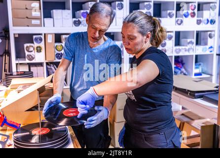 22 agosto 2022, Meclemburgo-Pomerania occidentale, Güstrow: I dipendenti della società discografica 'questione di fatto' controllano e imballano i record appena pressati nelle loro copertine. L'azienda, che attualmente ha cinque dipendenti, produce record per diverse settimane in un'ex sala patata che ha dovuto essere ampiamente convertito per la produzione di dischi. Con una forza di 150 tonnellate, i dischi di lunga durata sono prodotti sulle presse a 200 gradi Celsius da cloruro di polivinile (PVC). Ogni anno devono essere premuti tra 250.000 e 300.000 record. Secondo l'Associazione tedesca dell'industria musicale, ov Foto Stock