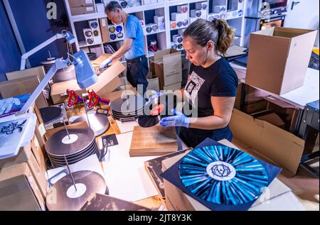 22 agosto 2022, Meclemburgo-Pomerania occidentale, Güstrow: I dipendenti della società discografica 'questione di fatto' controllano e imballano i record appena pressati nelle loro copertine. L'azienda, che attualmente ha cinque dipendenti, produce record per diverse settimane in un'ex sala patata che ha dovuto essere ampiamente convertito per la produzione di dischi. Con una forza di 150 tonnellate, i dischi di lunga durata sono prodotti sulle presse a 200 gradi Celsius da cloruro di polivinile (PVC). Ogni anno devono essere premuti tra 250.000 e 300.000 record. Secondo l'Associazione tedesca dell'industria musicale, ov Foto Stock