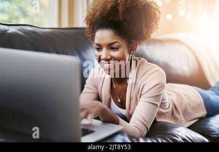 Che fine settimana sono stati fatti per. Una giovane donna attraente che usa il laptop mentre si rilassa a casa sul divano. Foto Stock