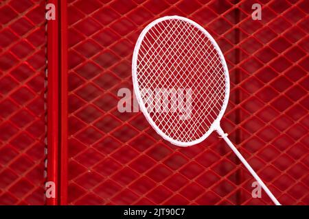 un racchetta di badminton è appesa alla griglia rossa da una fascetta per cavi per l'esposizione in occasione di eventi sportivi in mostra Foto Stock