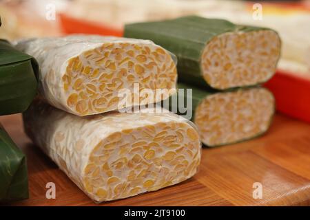 Tempe o tempeh avvolto in foglie di banana, è un cibo indonesiano tradizionale. Fatto di semi di soia fermentati. Foto Stock