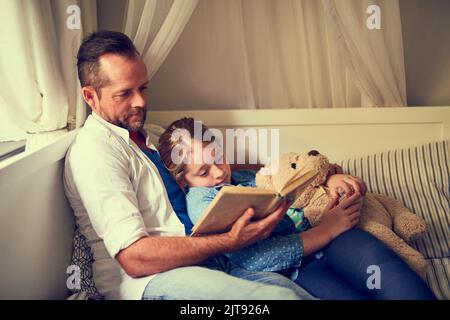 Un tempo... un padre che legge una storia alla sua figlia piccola a casa. Foto Stock