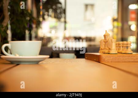 tazza di caffè vicino agli scacchi su un tavolo di legno, giocando a scacchi sopra una tazza di caffè in una pausa, pausa caffè Foto Stock