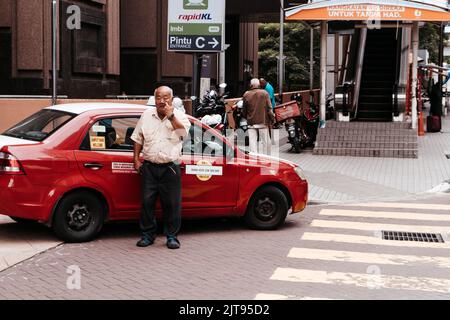 An aerial of street surrounded by buildings with driving cars and people in Kuala Lumpur Foto Stock