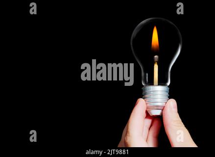 La mano contiene una lampadina a incandescenza in stile antico con un fiammiferi al suo interno. Foto Stock