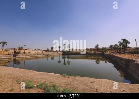 Antico lago nel complesso del Tempio di Karnak con le palme intorno, Egitto Foto Stock