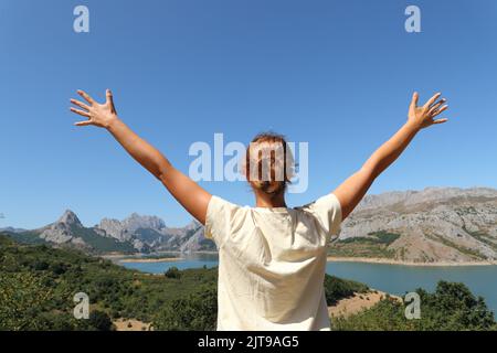 Vista posteriore ritratto di una donna felice che festeggia una vacanza in un paesaggio montano Foto Stock