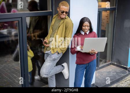 I giovani studenti usano i gadget nell'edificio dell'università Foto Stock