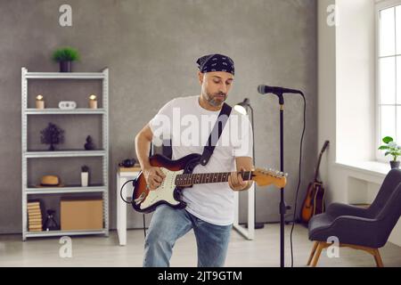 Musicista rock in piedi in sala prove e suonando musica sulla sua chitarra elettrica Foto Stock