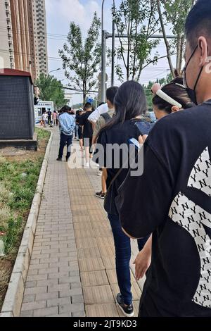 Un mercato verticale di residenti che si accingono a fare la fila per i test degli acidi nucleici su strada sotto la politica cinese di zero covid Foto Stock