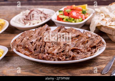 Kebab donatore di carne sul piatto. Kebab donatore di carne turco su sfondo di legno. Cucina turca tradizionale. Primo piano Foto Stock