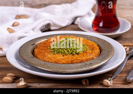 Kunefe. Cucina turca tradizionale. Kunefe con pistacchio su fondo in legno. Primo piano Foto Stock