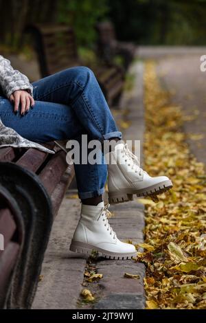 Gambe femminili in jeans e stivali bianchi con lacci. Foto Stock