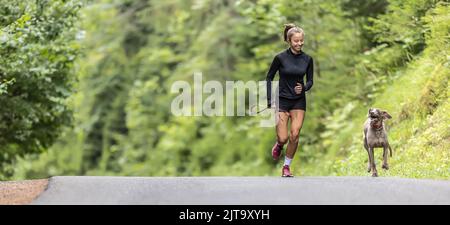 Ragazza adolescente ama correre all'aperto insieme al suo cane Weimaraner. Foto Stock