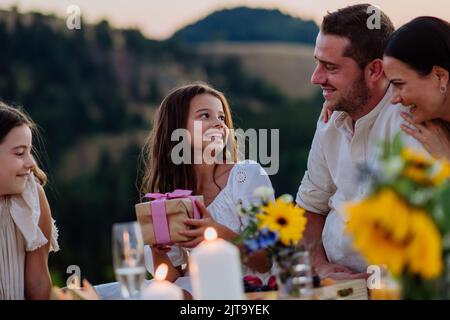 Famiglia felice con i bambini che festeggiano il compleanno con i regali all'aperto su un picnic nel parco. Foto Stock