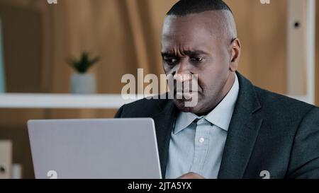 Frustrato afroamericano adulto anziano anziano uomo d'affari maturo anziano cittadino anziano uomo che guarda in schermo del laptop con guasto perso triste improvvisamente Foto Stock