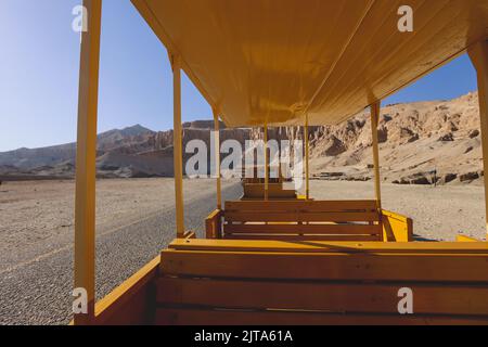 Veicolo pubblico giallo che sposta i turisti all'ingresso principale del Tempio mortuario di Hatshepsut vicino a Luxor, Egitto Foto Stock