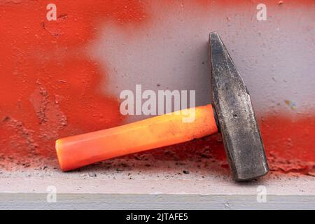 un martello in ferro con una maniglia in plastica corta su un ripiano dell'officina Foto Stock