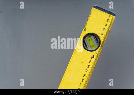 Bolla gialla livello edificio con marcature di lunghezza su sfondo grigio Foto Stock