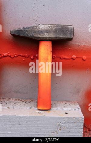 un martello in ferro con una maniglia in plastica corta su un ripiano dell'officina Foto Stock