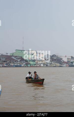 Pontianak, Indonesia - circa 2015: I residenti che attraversano il fiume Kapuas utilizzando una piccola barca di legno durante lo smog causato da un incendio terrestre. Foto Stock