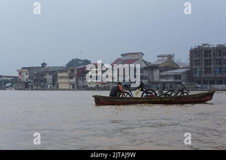 Pontianak, Indonesia - circa 2015: I residenti che attraversano il fiume Kapuas utilizzando una piccola barca a motore durante lo smog causato da un incendio terrestre. Foto Stock