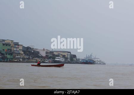 Pontianak, Indonesia - circa 2015: I residenti che attraversano il fiume Kapuas utilizzando una piccola barca a motore durante lo smog causato da un incendio terrestre. Foto Stock