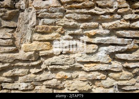 Facciata di un edificio in pietra di pietra naturale con ombre profonde alla luce naturale del sole Foto Stock