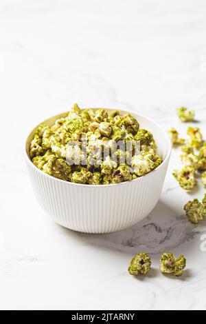 Popcorn verde vegano spirulina in una ciotola bianca. Cibo alternativo, dessert sano, dieta a base di piante. Foto Stock