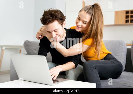 Giovane coppia che si diverti a navigare su Internet, guardando in un computer portatile Foto Stock