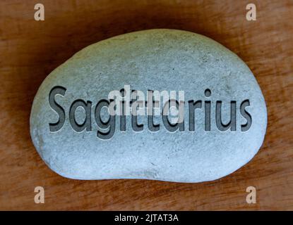 Testo del segno Sagittario zodiaco inciso su un fusto con fondo in legno. Concetto di segno zodiacale. Foto Stock